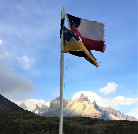 Image Title: Chilean and Magallanes Flags with Los Cuernos Mountains. [Photo: Open Door Travelers]