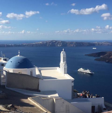 Image Title: The iconic view from the Greek Island of Santorini with the ship in the Harbor. [Photo: Open Door Travelers]